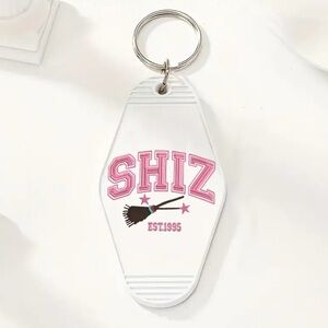 Wicked Themed Motel Keychain That is White and says “SHIZ” in Pink NEW